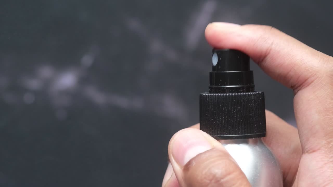 작은 금속 스프레이 병에서 무언가를 스프레이하는 사람