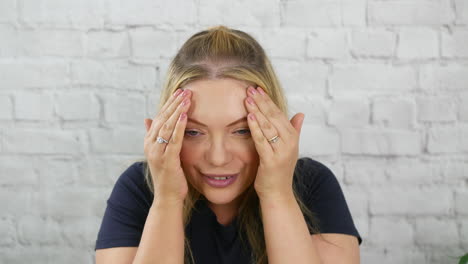 shocked and embarrassed blonde woman surprised and shy hiding behind her hands peeking