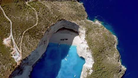 Aerial:-Panoramic-crane-shot-of-Navagio-beach-in-Zakynthos,-Greece-while-the-beach-is-in-shade