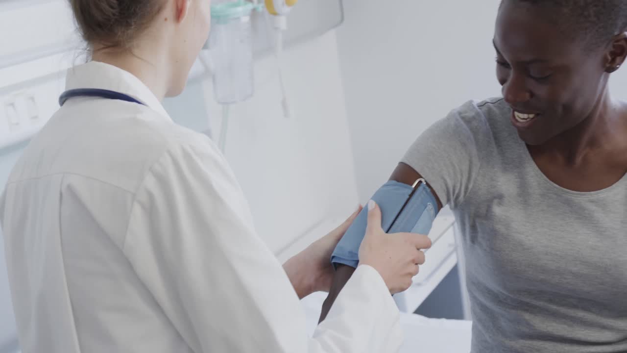 paciente femenina feliz y médico midiendo la presión arterial en el hospital, en cámara lenta.
