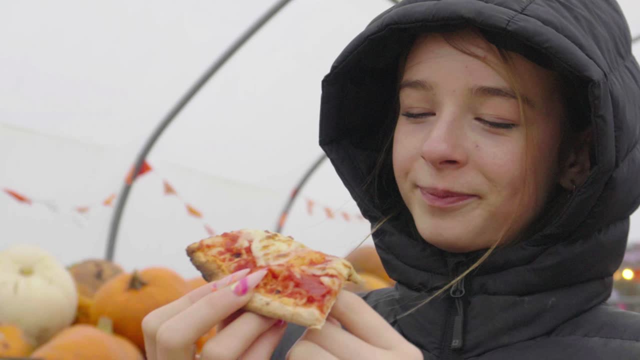 una joven adolescente disfrutando de la pizza margarita en un evento de festival