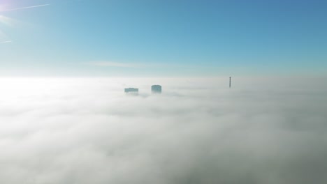 sunlit aerial winter cloud journey: drone moves forward towards towering skyscrapers piercing through inversion clouds revealing city views