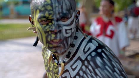 extreme closeup portrait of mayan or aztec dancer with painted face performing for the camera