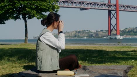 woman taking photos in a park near the bridge