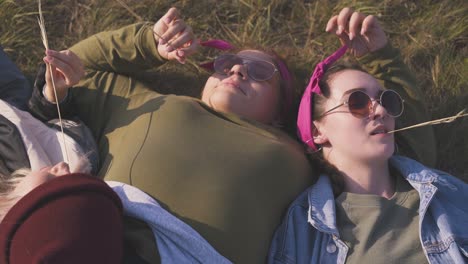 chicas con pajas descansan en la hierba en el campamento al atardecer