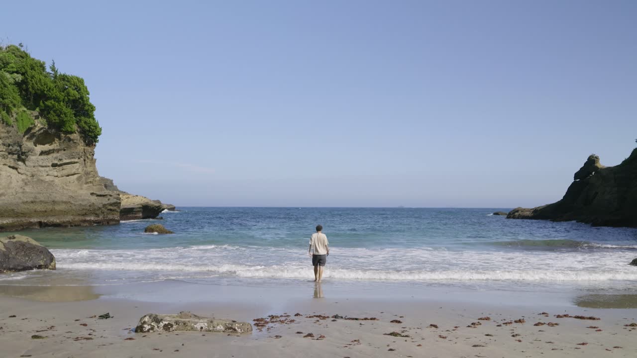 Lone male walking towards ocean with big waves, depression concept