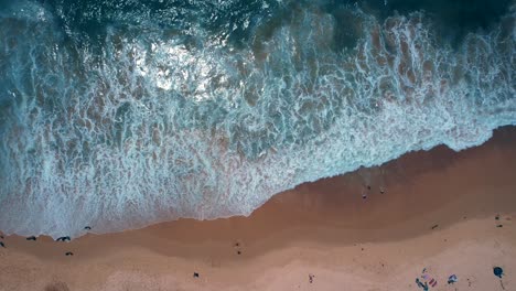 Luftdrohne-über-Dem-Kopf,-Vorbeiflugaufnahme-Von-Wellen,-Die-Auf-Den-Strand-Krachen