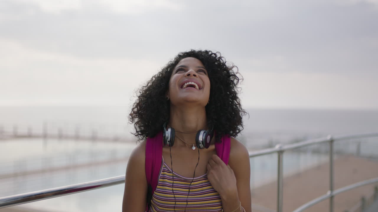 portrait of beautiful mixed race woman by seaside swimming pool laughing cheerful outdoors