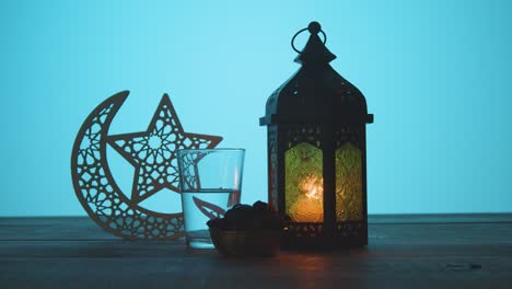 tracking shot of a lantern water and dates on a table during dusk ramadan celebrations