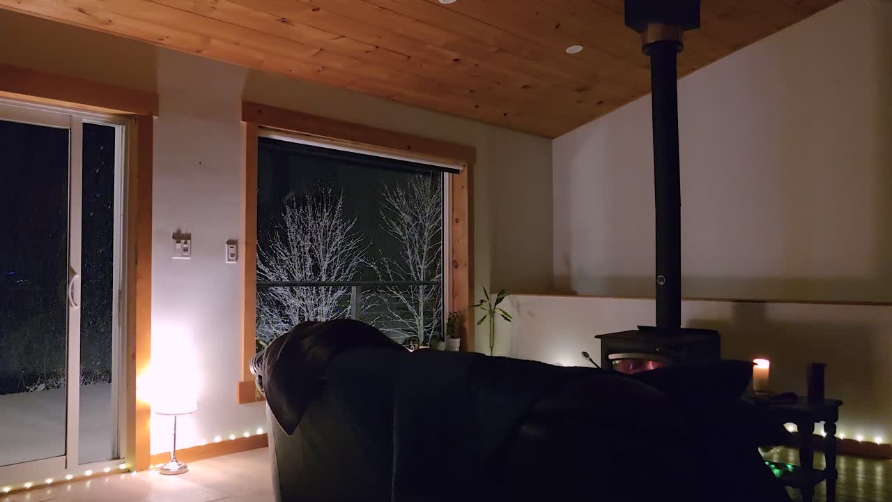 Snowfall View From A Glass Window Of A Cozy Home With Fireplace During Winter. Static Shot