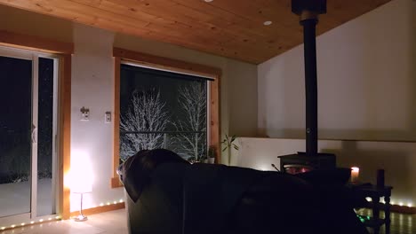 snowfall view from a glass window of a cozy home with fireplace during winter. static shot