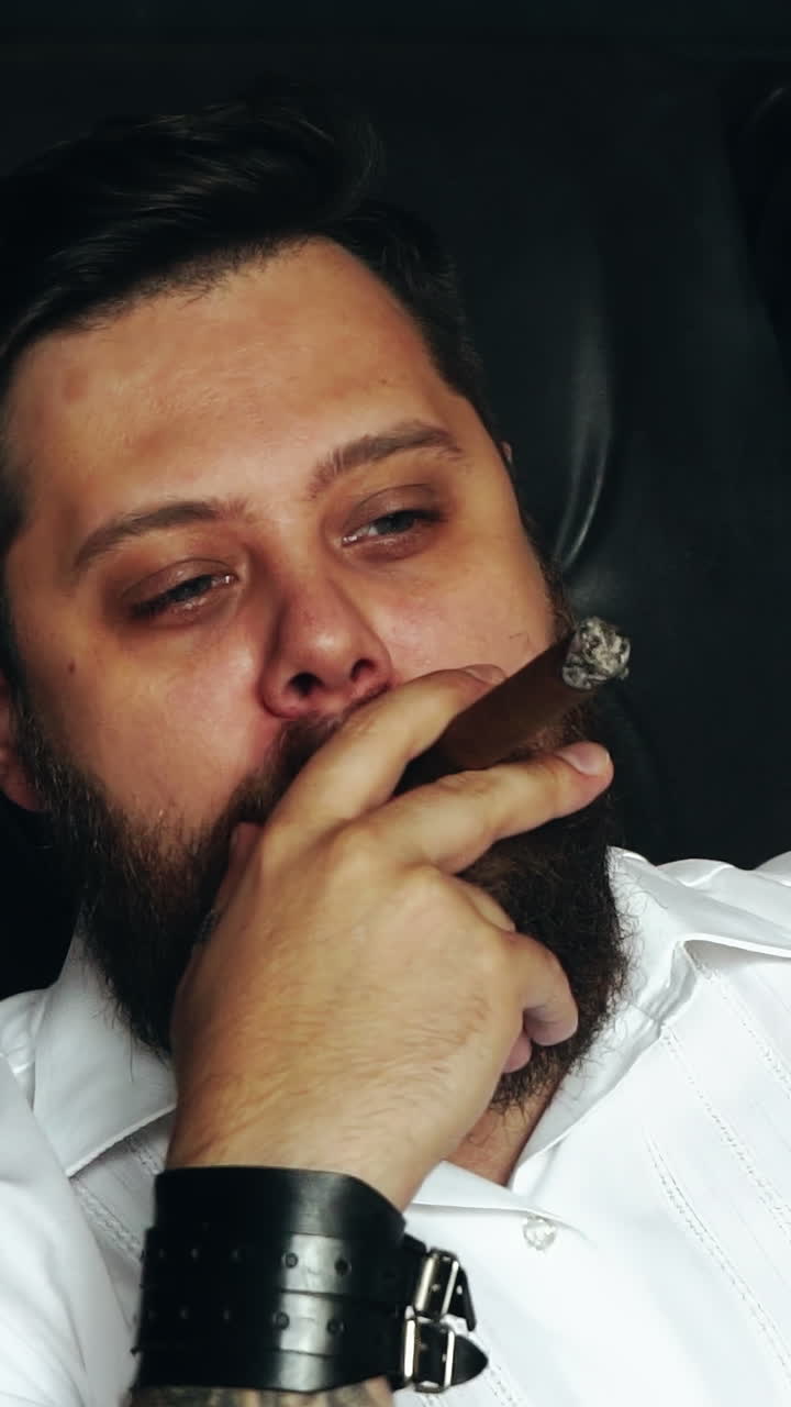 Brutal man smoking cigar. Handsome bearded man on serious face holding cigar in studio