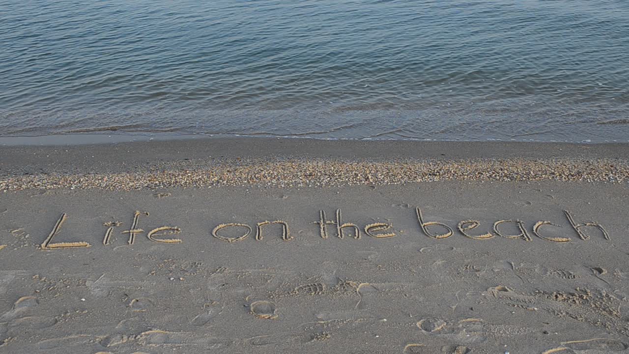 Inscription on sand, the beach. Life on the beach concept - inscription on a beach sand with coming wave