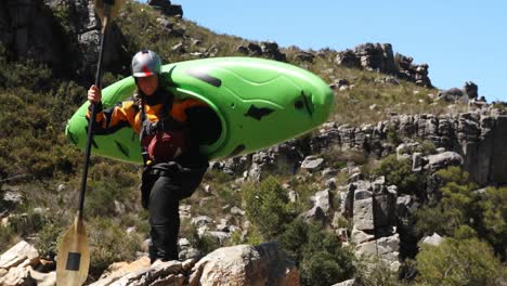 vrouw met kajak en peddel loopt naar de rivier 4k