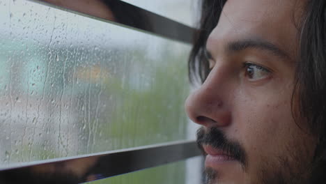hombre mirando por la ventana a la lluvia