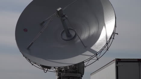 large satellite dish and truck against sky