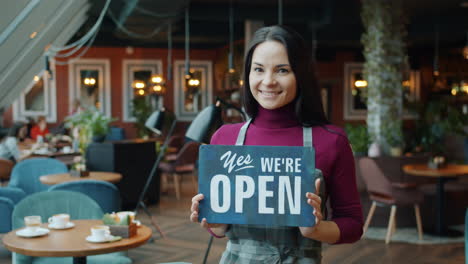 woman holding open sign in cafe