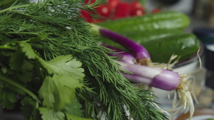 Green herbs and vegetables on kitchen table at home