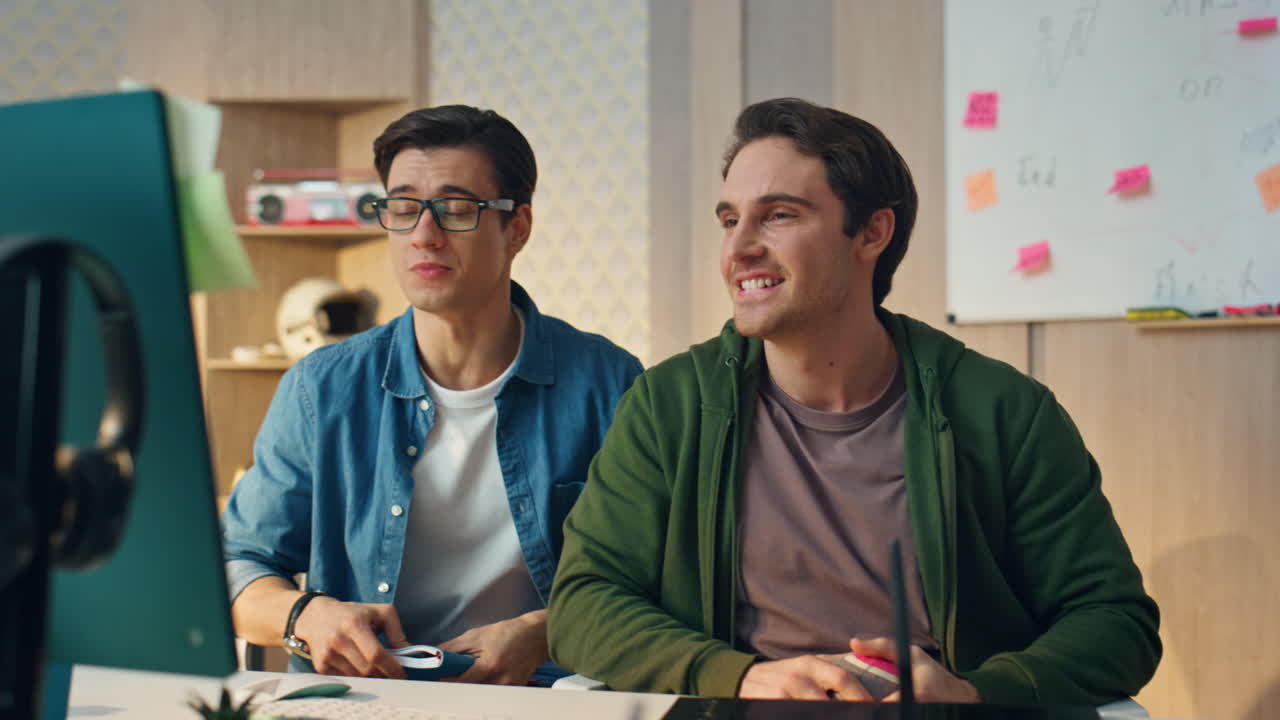 긍정적 인 남자 들 은 사무실 에서 컴퓨터 비디오 통화 를 하고 있다. 동료 들 은 모니터 를 보고 있다