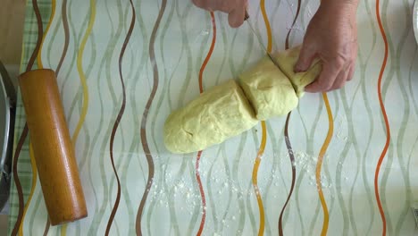 woman hand cut shape in rolling-pin dough, top view footage