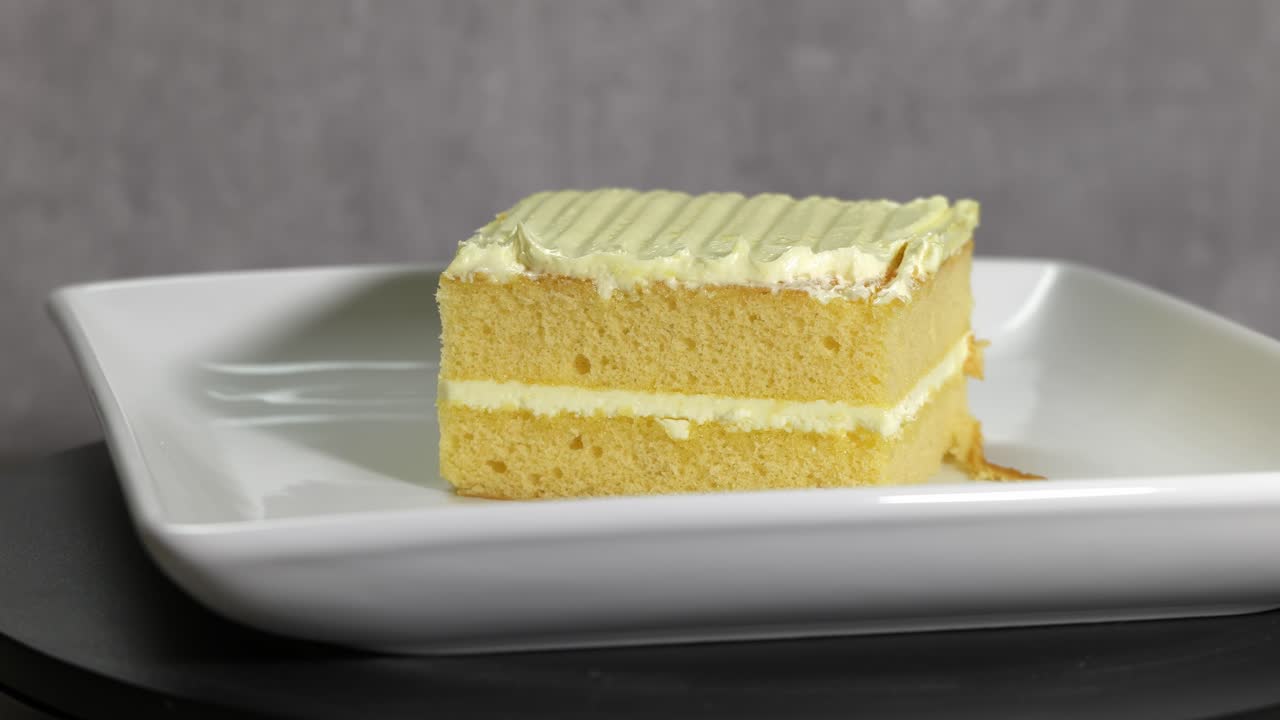 A Slice of Yellow Frosted Cake on a White Plate