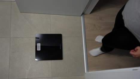 pregnant woman stands on bathroom scale checking weight during pregnancy