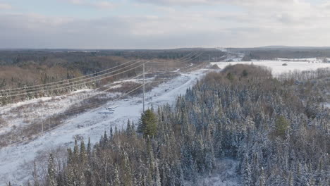 transmission lines in a snowy rural winter forest landscape, aerial