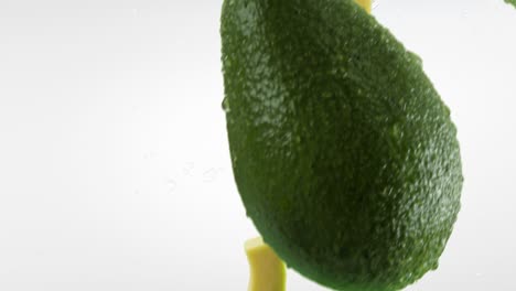 aguacate con rebanadas y salpicaduras cayendo sobre un fondo blanco