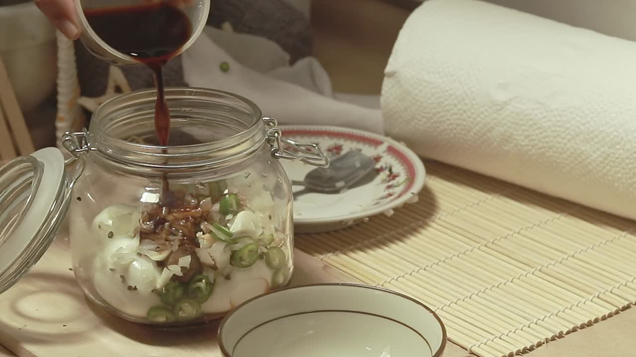 Pouring soy sauce after adding the spices to a mason jar with hard boiled eggs showing the authentic recipe for mayak gyeran or korean marinated eggs