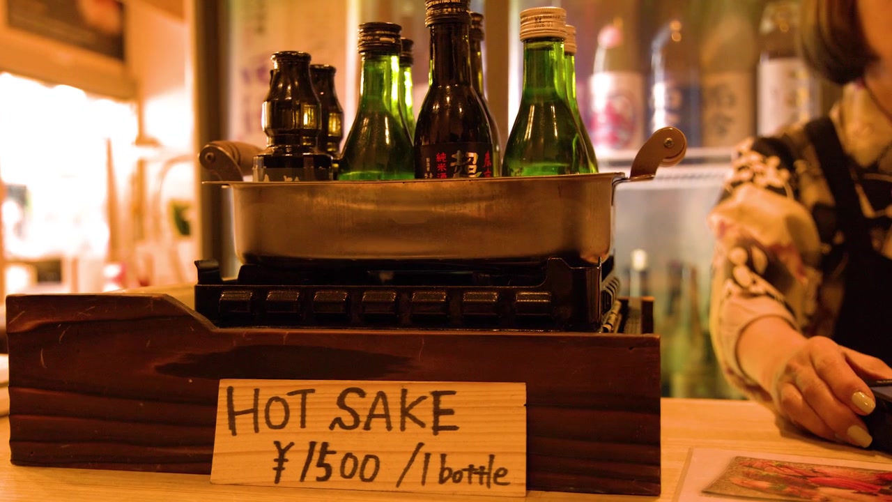 Sake-Flaschen wärmen sich in einem Metallbad in einem japanischen Restaurant
