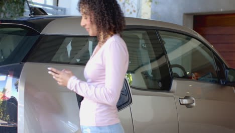 Charging electric car, woman using smartphone while waiting in garage