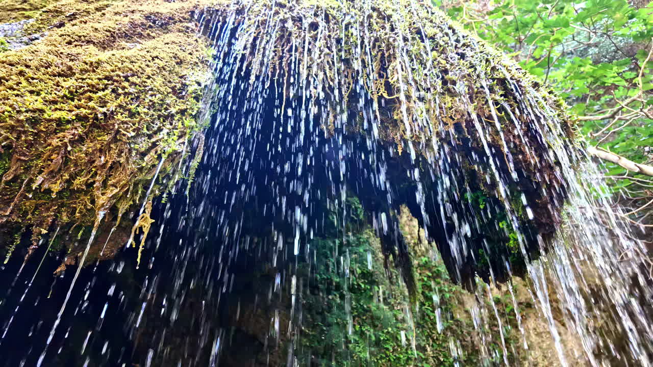 Water flows gently over a moss-covered rock formation, creating thin, delicate streams at Richtis Gorge