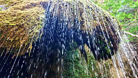 water flows gently over a moss-covered rock formation, creating thin, delicate streams at richtis gorge