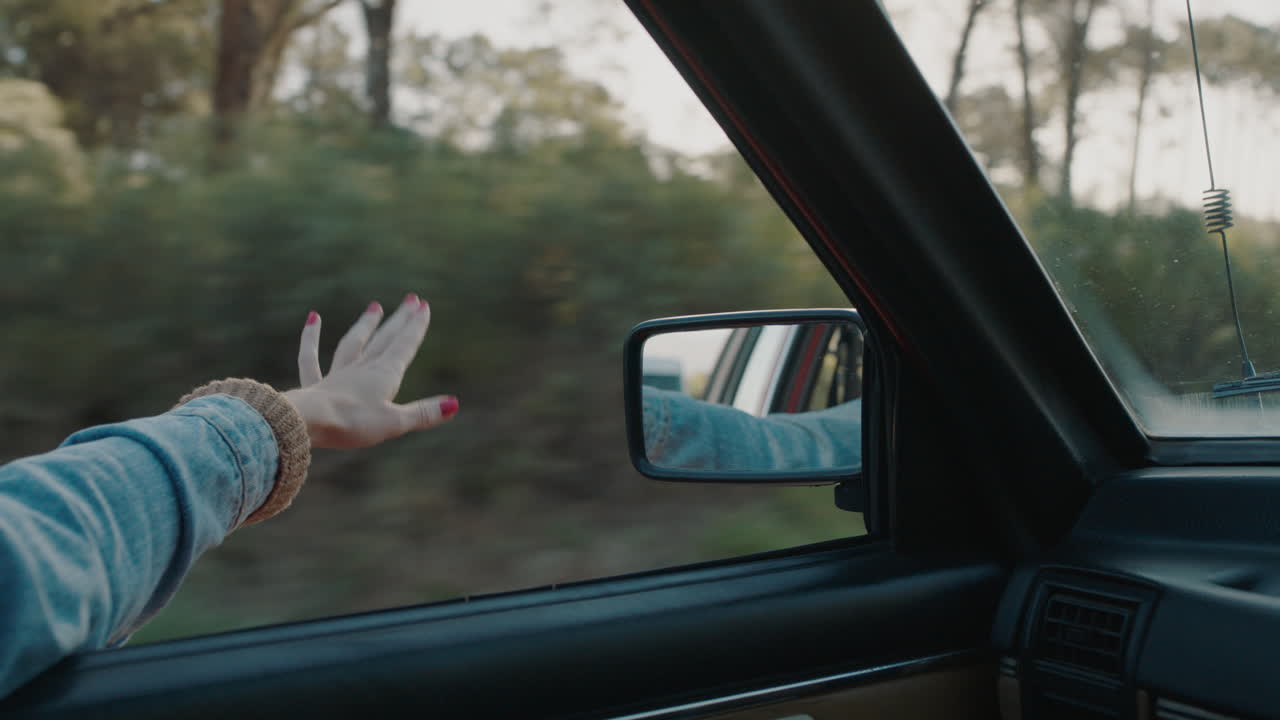mujer con la mano en la ventana del coche sintiendo el viento soplando a través de los dedos conduciendo en el campo viajando en vacaciones de verano viaje por carretera disfrutando de la libertad en la carretera