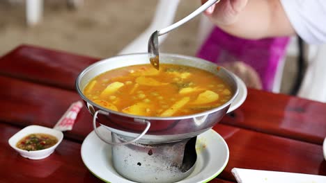 ladling yellow curry into a bowl