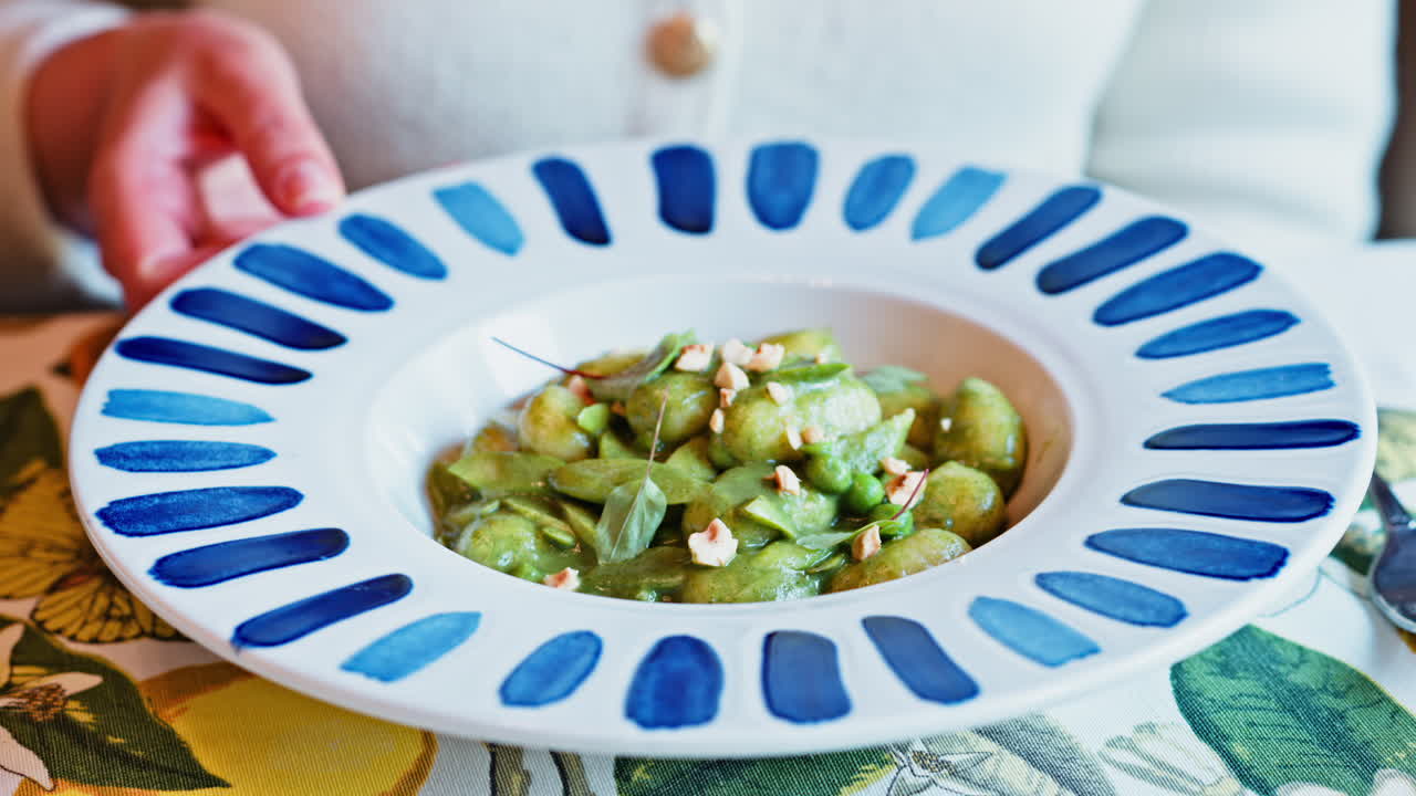 Woman eating gnocchi with pesto at an Italian restaurant