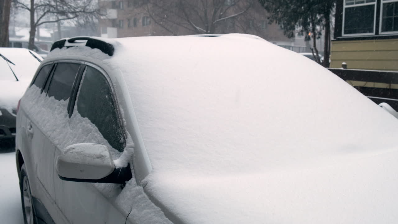 panorámica sobre un coche cubierto de nieve en una tormenta de nieve