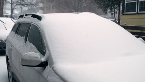 pan over a snow-covered car in a snowstorm