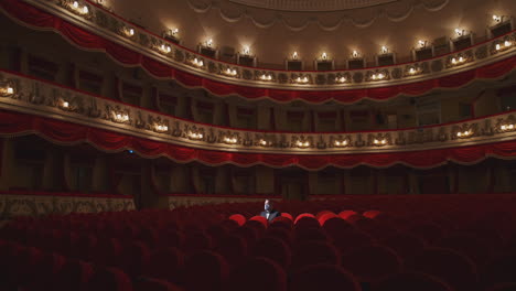 alone man in theater hall. rows of empty red cinema chairs in theatre during the period of the covid-19