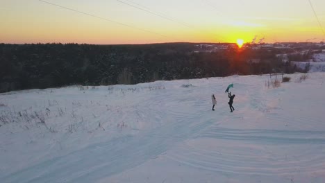 happy family relaxes on snowy field against orange sky