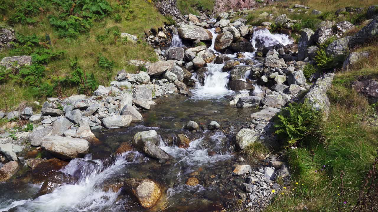 tilting shot revealing the gushing mountain stream flowing down the side of Helvellyn in the Lake District Cumbria, England