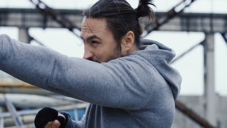 sporty young boxer doing punches in the air during morning workout on a cloudy morning