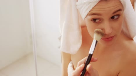 Woman-applying-make-up-on-her-face-in-bathroom