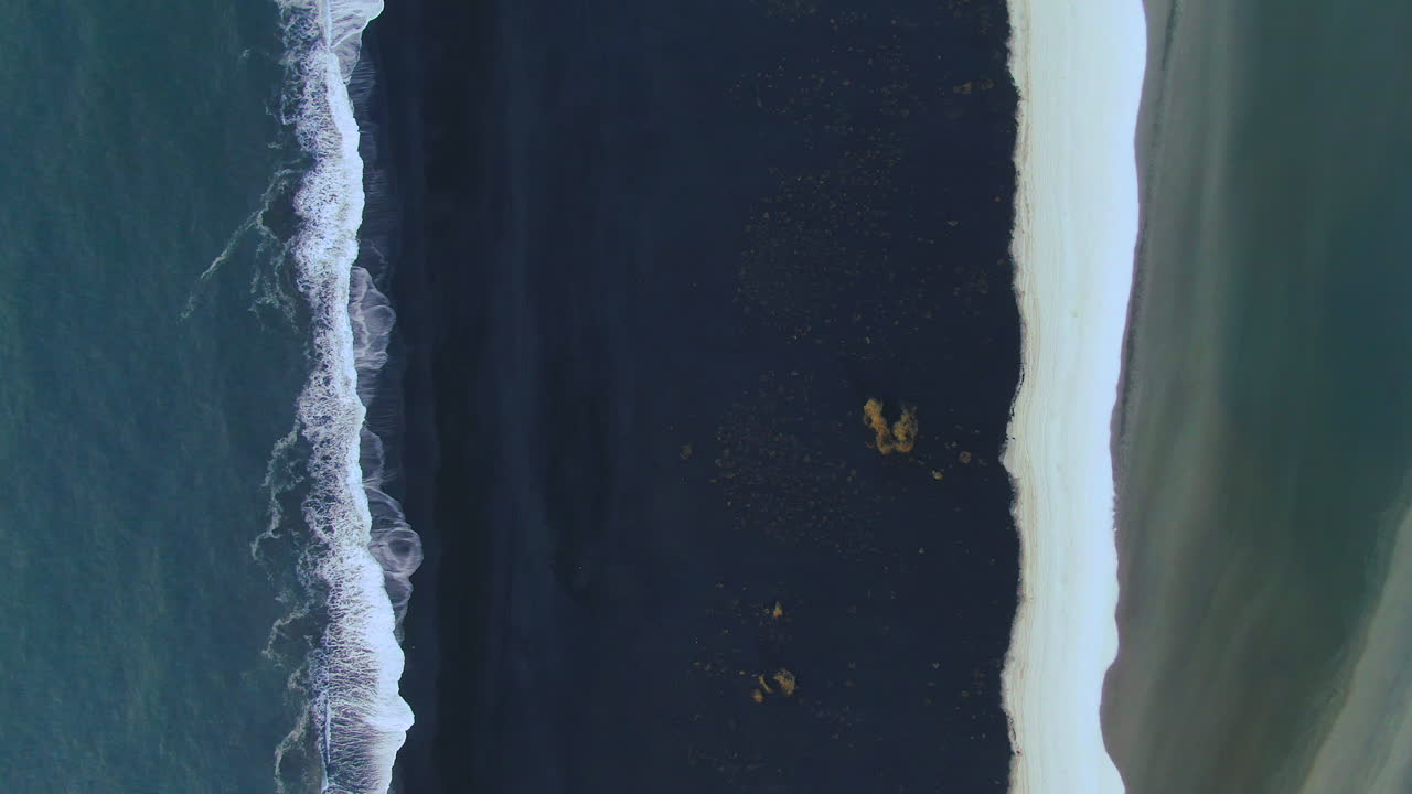 Slow motion view of waves gently crashing to the shore in Iceland