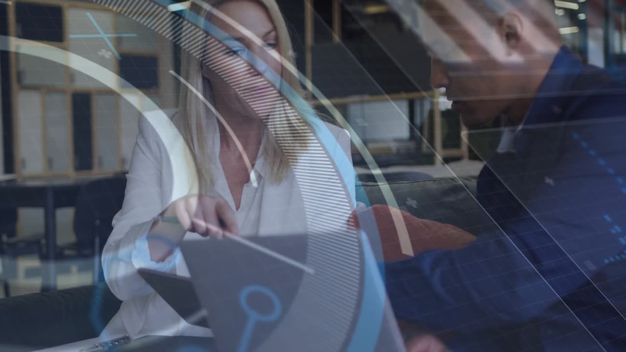 Retrieving tablet, two business professionals tapping and pointing at slides as graphics swirling