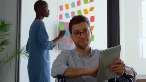 vista frontal de un joven empresario caucásico discapacitado trabajando en una tableta digital y mirando a la cámara 4k