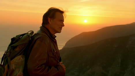man gazing at sunset over mountains