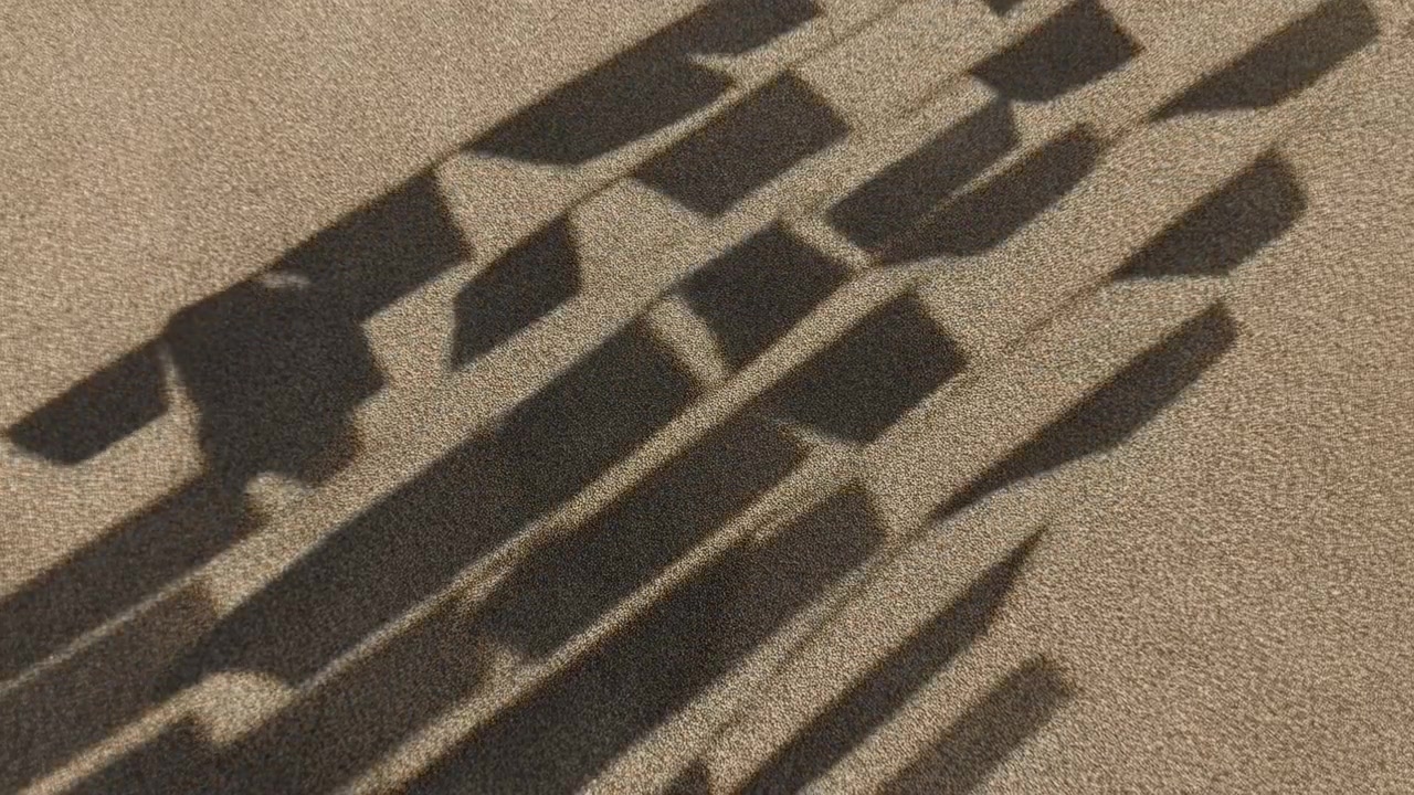 Repeating dark shadow shapes move diagonally across coarse beige looped carpet, creating abstract geometric contrast, warm neutral tones, and subtle interior texture under strong directional light