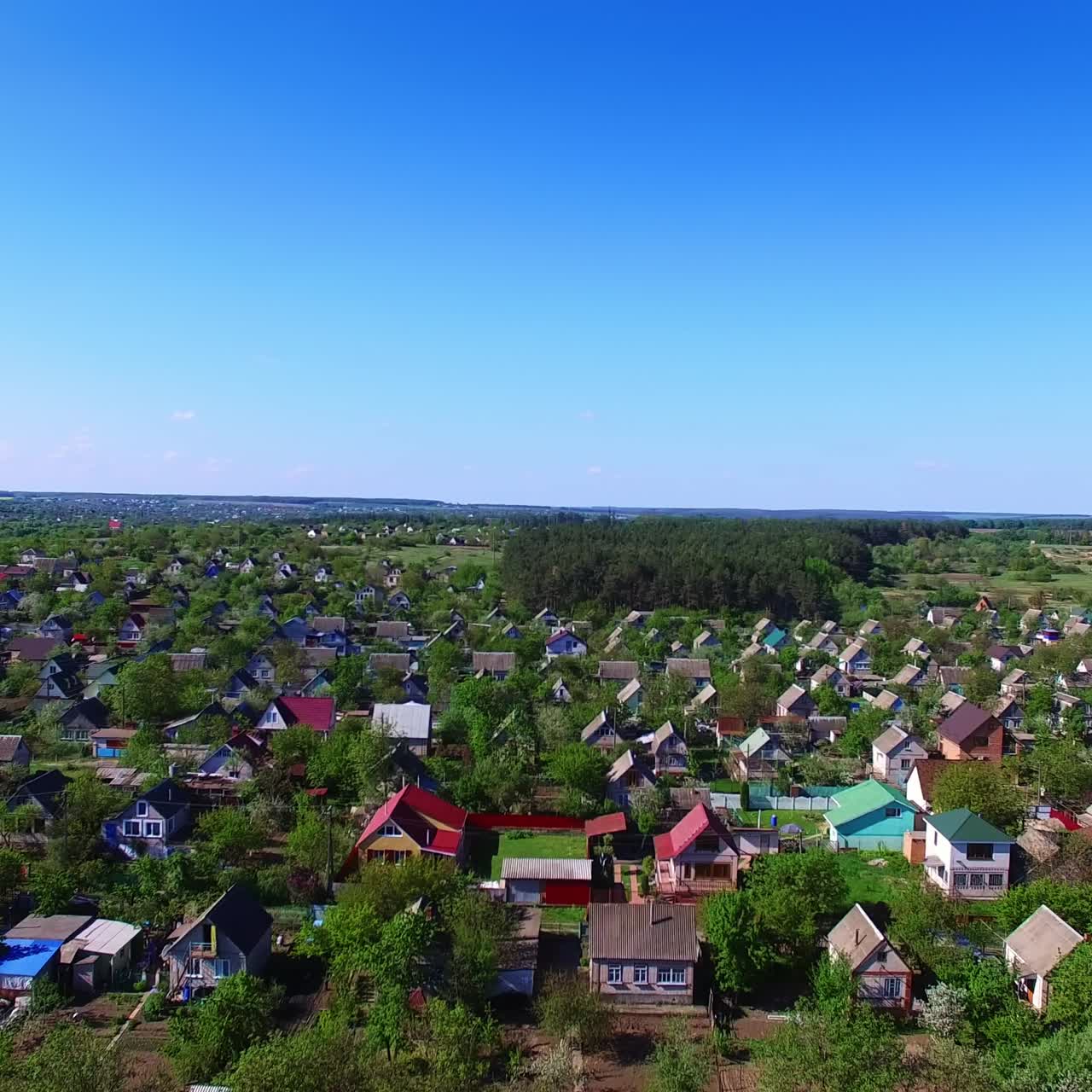 Quite big village with beautiful cottages among the green trees. Countryside with lovely nature around on sunny daytime. Blue clear sky at backdrop