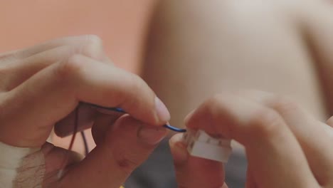 close-up of hands connecting electric cable wires, showing delicate work and attention to detail, likely related to electronics